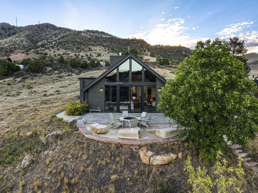 The glass gable and fire-pit patio from above, with the hills behind