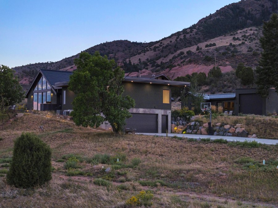 The house at dusk with red sandstone rising behind it