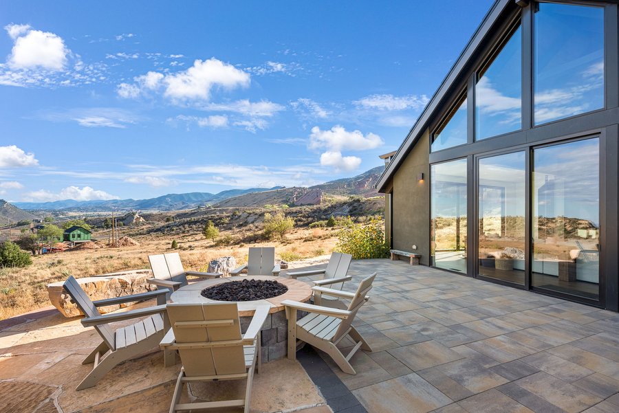 Patio with a fire pit and Adirondack chairs beside the glass gable