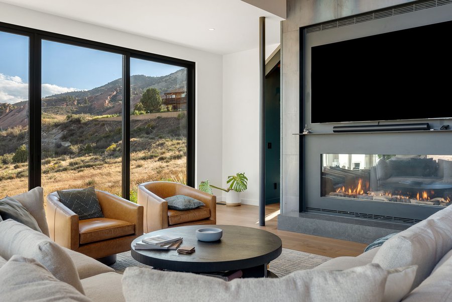Great room seating facing a linear fireplace, with leather armchairs and mountain views