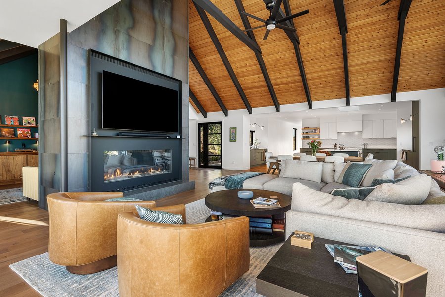 Great room fireplace wall with a wide TV and tan leather chairs