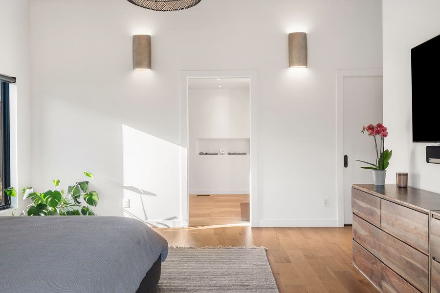 Bright hallway with wall sconces beside the primary bedroom
