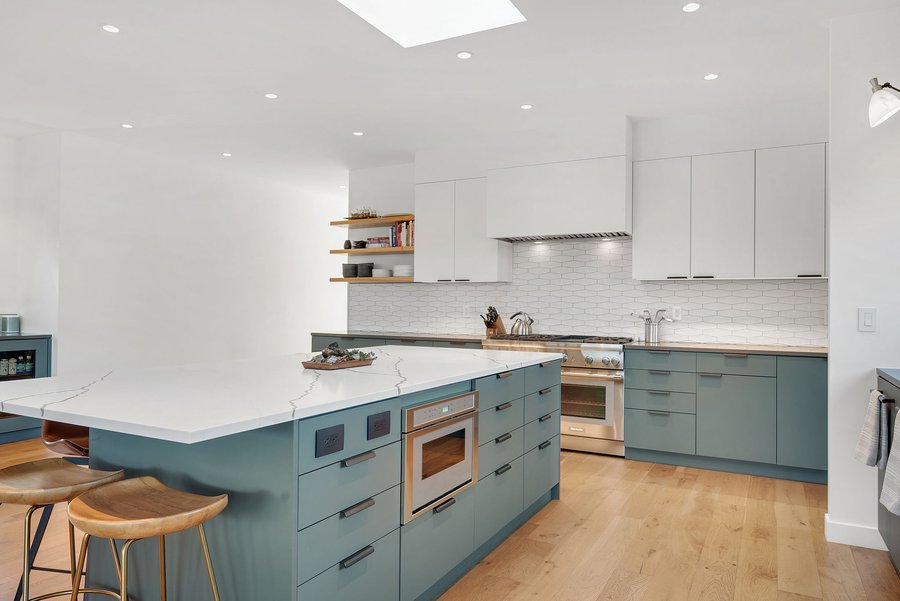 Kitchen island with a marble top and teal-gray cabinetry