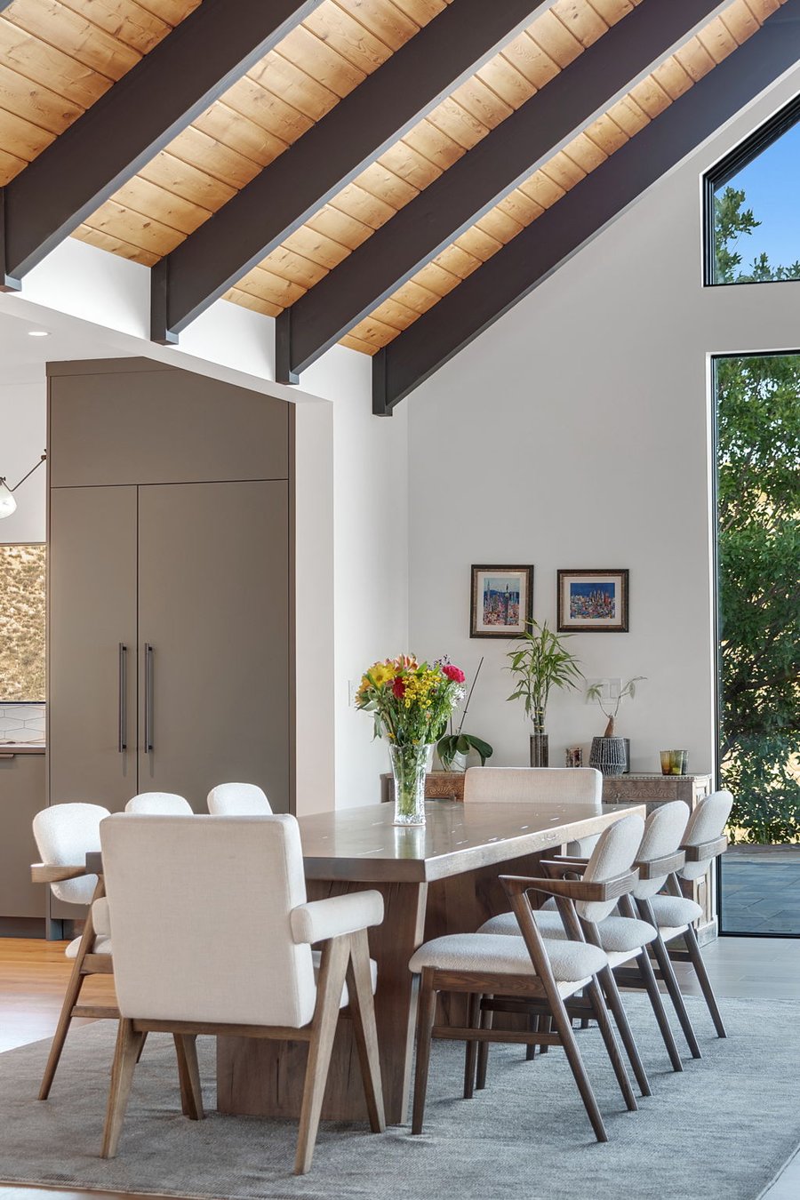 Timber-beamed ceiling above a tall pantry cabinet and fresh flowers