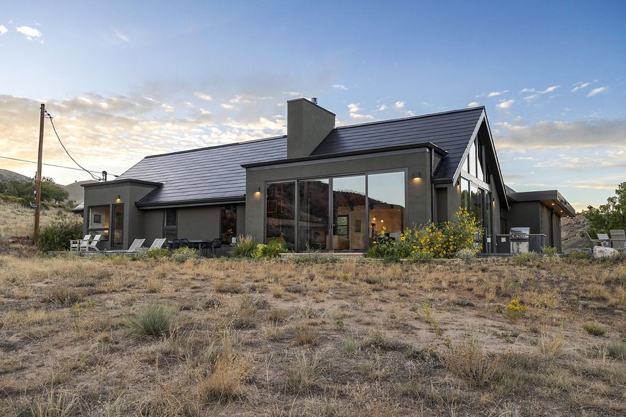 The house glowing at dusk across the open field
