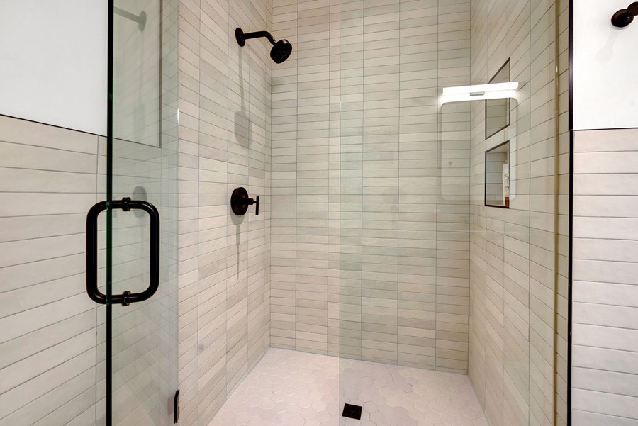 Walk-in glass shower with stacked cream tile