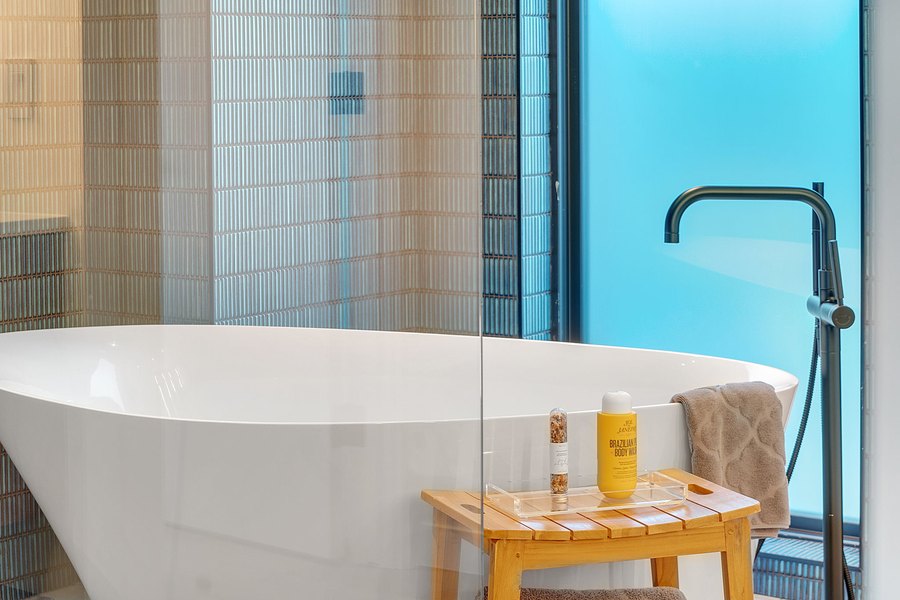 Freestanding tub with a black floor-mounted faucet and a view of the sky