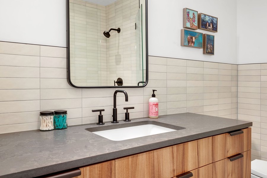 Guest bath vanity with a black-framed mirror and a gray stone counter