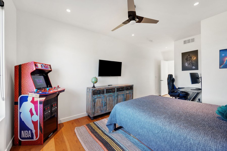 Bedroom with an NBA Jam arcade cabinet, a bed and a desk
