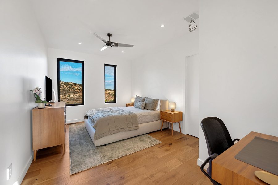 Bedroom with a queen bed, ceiling fan, desk and a window onto the hillside