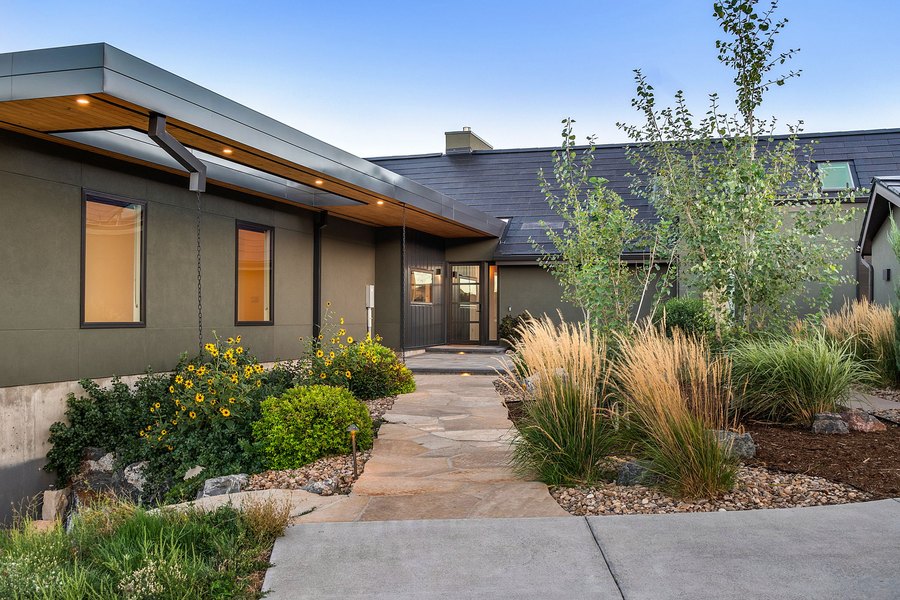 Flagstone entry path through the courtyard at dusk, with grasses, sunflowers and the lit main house
