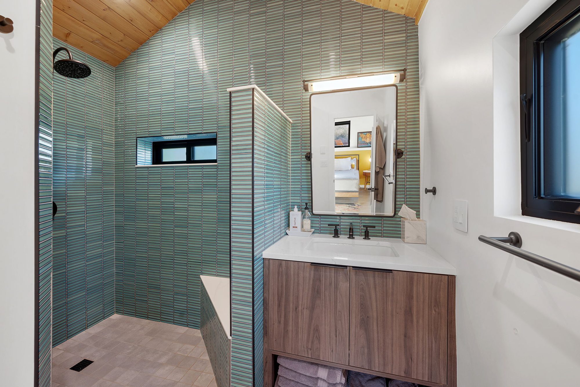 Guesthouse bathroom with green vertical tile and a walk-in shower