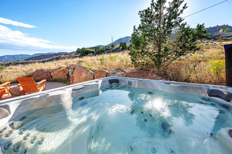 Bubbling hot tub with orange chairs and foothills behind