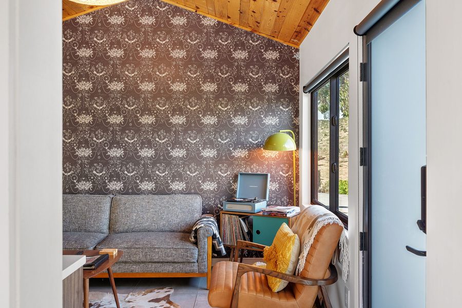Guesthouse sitting area by the window with a gray sofa and leather chair