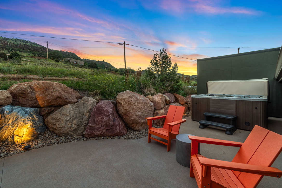 Guesthouse hot tub, boulders and orange chairs under a sunset sky