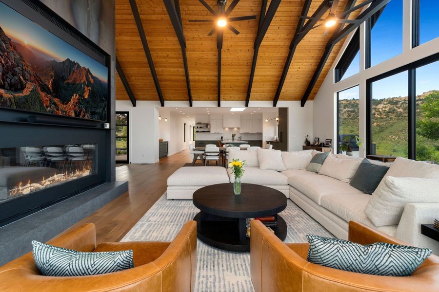 Great room with a timber ceiling, sectional sofa, fireplace and open kitchen beyond